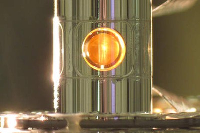 A deuterium and tritium capsule, sphere in window at center, inside a cylindrical hohlraum container about 0.4 inches tall.