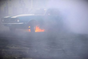 Fire burns under a car as it performs a burnout during Summernats.