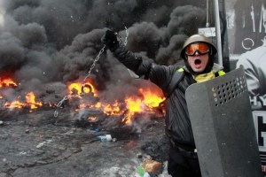 A pro-European protester swings a metal chain during clashes with riot policemen