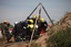 Emergency rescue workers attempt to free trapped illegal miners at a disused gold mine shaft near, Benoni, South Africa, Sunday, Feb. 16, 2014. The South African Press Association reported Sunday that rescue teams were able to speak to about 30 miners near the top of an old gold mine shaft whose entrance was covered by a large rock. Those miners said as many as 200 others were trapped further down a steep tunnel at the mine in Benoni, on the outskirts of Johannesburg