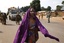 At PK12, the last checkpoint at the exit of the town, a Muslim woman who was on a truck attacked by looters walks to join another vehicle, as Chadian soldiers protect the lorry as thousands of Muslim residents from Bangui and Mbaiki flee the Central African Republic capital Bangui in a mass exodus using cars, pickups, trucks, lorries and motorcycles, Friday, Feb. 7, 2014.