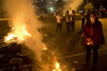 A demonstrator stands next to a burning barricade during an opposition protest outside La Carlota airport in Caracas, Venezuela, Tuesday, Feb. 18, 2014. Members of the opposition are protesting after their leader Leopoldo Lopez surrendered to authorities Tuesday. Lopez was being sought by authorities for allegedly inciting violence during protests last week in which three people were killed as government forces clashed with protesters.