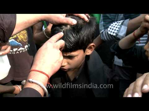 Young Shiite Muslim cries as an elder makes a cut on his forehead during Muharram