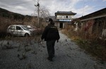 File - Former resident Susumu Ikeda walks past an overgrown garden during a visit to his home in the abandoned town of Namie, northeastern Japan, just outside the 20 kilometer exclusion zone around the crippled Fukushima Dai-ichi nuclear plant. Sunday, Nov. 20, 2011.