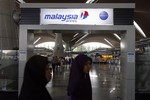 Passengers walk past a signboard of Malaysia Airlines at Kuala Lumpur International Airport in Sepang, outside Kuala Lumpur, Malaysia, Saturday, March 8, 2014.