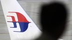 A man looks out from a viewing gallery as a Malaysia Airlines aircraft sits on the tarmac at Kuala Lumpur International Airport in Sepang, Malaysia, 9 March