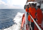 A member of Indonesian National Search and Rescue Agency (BASARNAS) uses a binocular to scan the horizon during a search operation for the missing Malaysia Airlines Boeing 777 conducted on the waters of the Strait of Malacca off Sumatra island, Indonesia, Wednesday, March 12, 2014.