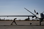 File - After taxiing in an MQ-9 Reaper, Airman 1st Class Jon Mann walks under a Reaper's wing to place wheel chocks to prevent accidental movement April 24, 2013 at Holloman Air Force Base, N.M.