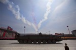 A North Korean missile rolls by as colored smoke trails, left by flying aircraft, streak the sky during a mass military parade on Kim Il Sung Square in Pyongyang to mark the 60th anniversary of the Korean War armistice Saturday, July 27, 2013.