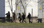 Unidentified armed men search an area close to an Ukrainian military unit in Simferopol, Crimea, on Tuesday, March 18, 2014.