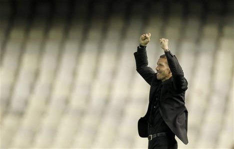 Atletico de Madrid coach Diego Simeone of Argentina, salutes supporters after winning the second leg semifinal Europa League soccer match against Valencia at the Mestalla stadium, in Valencia, Spain, Thursday, April 26, 2012.