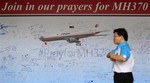 A man walks past a message board for passengers aboard a missing Malaysia Airlines plane, at a shopping mall in Petaling Jaya, near Kuala Lumpur, Malaysia, Friday, March 21, 2014.