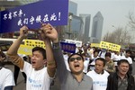 Chinese relatives of passengers onboard the missing Malaysia Airlines plane, flight MH370, shout in protest as they march towards the Malaysia embassy in Beijing, China, Tuesday, March 25, 2014.