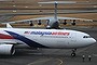 Mystery: A Malaysia Airlines plane prepares to go onto the runway and pass by a stationary Chinese Ilyushin 76 search aircraft (top) at Perth International Airport. 