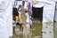 The United Nations Mission in South Sudan (UNMISS) and other agencies have started relocating thousands of internally displaced persons (IDPs) sheltering in the protection of civilians area of the Tomping IDP camp outside of Juba to a new location at UN house in the capital due to heavy rains and flooding.  A mother and children walk amongst flooded shelters at the Tomping IDP camp, 12 March 2014.