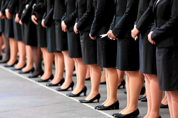 A Japan Airlines group companies' new employee, third from right, holds a paper plane while standing in line with other new employees during a welcoming ceremony at the company's hangar near Haneda Airport in Tokyo, Japan.