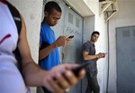 Students gather behind a business looking for a Internet signal for their smart phones in Havana, Cuba, Tuesday, April 1, 2014.