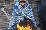 A pro-Russia protester warms herself next to a fire during a rally outside a regional government building in Donetsk, in eastern Ukraine April 11, 2014. Ukraine's prime minister offered on Friday to boost local powers in the regions in an effort to undercut pro-Russia separatists who have occupied official buildings in Russian-speaking cities in eastern Ukraine. But separatists still occupied the main regional offices in Donetsk, while in Luhansk armed rebels were refusing an offer of non-prosecution by the Kiev authorities in exchange for them laying down their weapons and quitting the regional offices of the state security service.REUTERS/Gleb Garanich (UKRAINE - Tags: POLITICS CIVIL UNREST TPX IMAGES OF THE DAY)