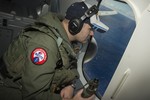 Naval Aircrewman (Operator) 2nd Class Karl Shinn, assigned to Patrol Squadron (VP) 16, searches out the window of a P-8A Poseidon while flying over the Indian Ocean during a search mission to locate Malaysia Airlines flight MH370, 10 April, 2014.