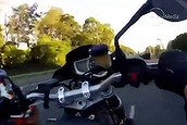 A Brisbane motorbike rider pops a wheelie while another rider passes to his left.