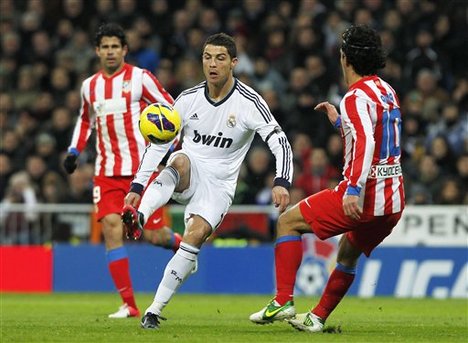 Real Madrid's Cristiano Ronaldo from Portugal, center, controls the ball against Atletico de Madrid's Arda Turan from Turkey, right, during a Spanish La Liga soccer match at the Santiago Bernabeu stadium in Madrid, Spain, Saturday, Dec. 1, 2012.