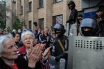 Elderly women applaud masked pro-Russian demonstrators who stormed the military Prosecutor's Office in Donetsk, eastern Ukraine, Sunday, May 4, 2014.