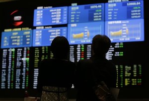 A couple looks at the electronic stock boards at the Tokyo Stock Exchange in Tokyo, Friday, June 21, 2013.