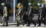 Chinese paramilitary police on patrol walking past an ethnic minority woman on the streets of Urumqi in western China's Xinjiang province, Monday, Sept. 21, 2009.