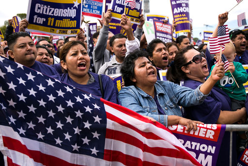 (L to R)  Lorena Ramirez, of Arlington, Virginia, holds up an American flag as she cheers with her friend Lilia Beiec during a rally in support of immigration reform, in Washington, on October 8, 2013 in Washington, DC.