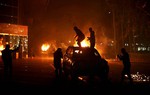 File - In this Sunday, March 2, 2014 photo, protesters stand atop a vehicle as others burn in front of the National Conference Hall, in Tripoli, Libya.