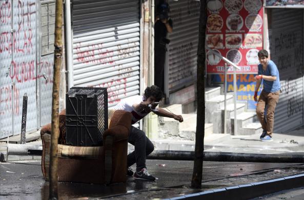 A protester uses a slingshot to throw rocks as they clash with riot police in Istanbul