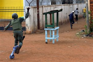 African Union MISCA troops from Cameroon throw a stunt grenade at protesters who set up barricades throughout the town, Thursday, May 29, 2014 in Bangui, Central African Republic.