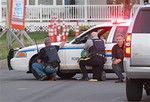 Police officers take cover behind their vehicles in Moncton, New Brunswick, on Wednesday June 4, 2014.