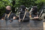 Ukrainian troops stand atop of a vehicle as they leave the scene of fighting in Mariupol, eastern Ukraine, Friday, June 13, 2014.