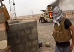 This image made from video posted by Iraqi Revolution, a group supporting the al-Qaida breakaway Islamic State of Iraq and the Levant (ISIL) on Wednesday, June 11, 2014, which has been verified and is consistent with other AP reporting, shows a militant standing in front of a burning Iraqi Army Humvee in Tikrit, Iraq.