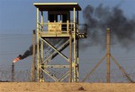 File - In this Monday, Oct. 6, 2003 file photo, an abandoned watchtower and lines of barbed wire are seen surrounding Iraq's largest oil refinery as smoke rises from a petroleum gas flare, in the city of Beiji, north of Baghdad. On Wednesday, June 18, 2014, a top Iraqi security official said Islamic militants of the al-Qaida-inspired Islamic State of Iraq and the Levant laid siege to Iraq's largest oil refinery late Tuesday night, threatening a facility key to the country's domestic supplies as part of their ongoing lightning offensive across the country. The Beiji refinery accounts for a little more than a quarter of the country's entire refining capacity and any lengthy outage at Beiji risks long lines at the gas pump and electricity shortages, adding to the chaos already facing Iraq.