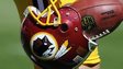 A player carries a Redskins helmet with a football in it.