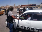 A fighter with the al-Qaida-inspired Islamic State of Iraq and the Levant (ISIL) distributes a copy of the Quran, Islam's holy book, to a driver in central northern city of Mosul, 225 miles (360 kilometers) northwest of Baghdad, Iraq, Sunday, June 22, 2014.