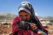 Syrian woman Lina kisses her two-year-old daughter outside her makeshift tent in Lebanon