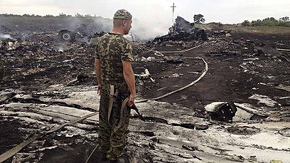 An armed pro-Russian separatist stands at a site of a Malaysia Airlines Boeing 777 plane crash in the settlement of Grabovo in the Donetsk region, July 17, 2014. 
(UKRAINE - Tags: TRANSPORT DISASTER CIVIL UNREST TPX IMAGES OF THE DAY)