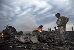 People walk amongst the debris, at the crash site of a passenger plane near the village of Grabovo, Ukraine, Thursday, July 17, 2014