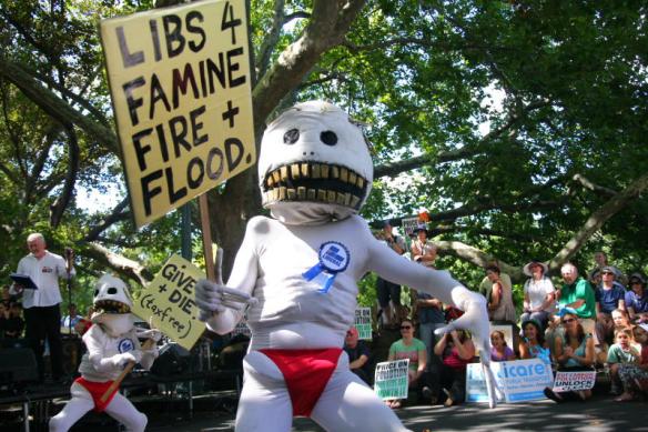 Tony Abbott clone with placard - 'Libs 4 Famine Fire + Flood'