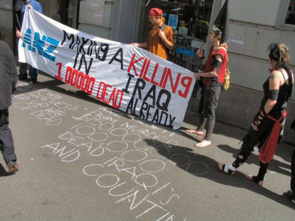 Protesters and 'pirates' with banner and chalked slogans on footpath