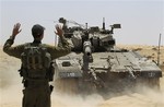 An Israeli soldier directs a tank, maneuvering near the border between Israel and Egypt, Monday, June 18, 2012.