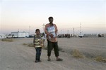 Displaced Iraqis from the Yazidi community carry humanitarian aid at the camp of Bajid Kandala at Feeshkhabour town near the Syria-Iraq border, in Iraq Saturday, Aug. 9, 2014.