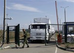 A Russian border guard opens a gate into the Ukraine for the first trucks heading into the country from the Russian town of Donetsk, Rostov-on-Don region, Russia, Friday, Aug. 22, 2014.