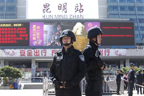 File - Armed policemen guard their positions in front of Kunming Railway Station in Kunming, in western China's Yunnan province, Sunday, March 2, 2014.