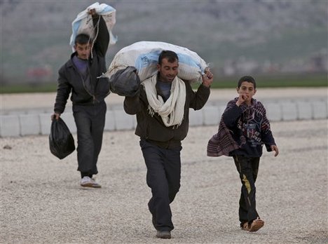 A group of Syrian, fleeing violence in their country, walk towards the Turkish border near Reyhanli, Turkey, Thursday, March 15, 2012.