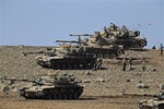 Turkish soldiers stand atop and around their tanks as they hold their positions on a hilltop in the outskirts of Suruc, at the Turkey-Syria border, overlooking Kobani in Syria where fighting had ben intensified between Syrian Kurds and the militants of Islamic State,group Monday, Oct. 6, 2014.