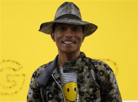 Singer Pharrell Williams poses during a news conference for the exhibition "GIRL" at the Perrotin Gallery in Paris, Monday, May 26, 2014. Williams curated an exhibition encompassing around 40 art pieces, presenting their visions of femininity, muses, female creativity and freedom. The show opens on May 27 and runs through June 27, 2014. The piece behind Williams is "GIRL" by French artist Guy Limone.